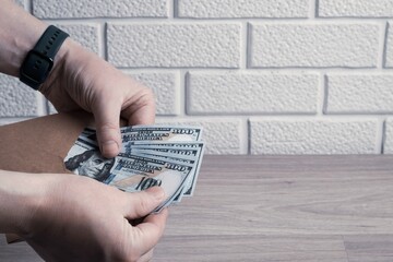 Male hands count dollar bills in a paper envelope. Bonus, reward, benefits concept