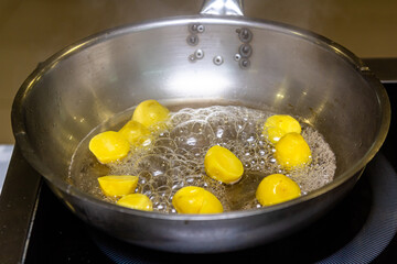 The cook is frying potato balls in a frying pan