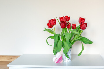 Red tulips in a vase on the shelf at home.  Bouquet for Mothers day, home decoration 