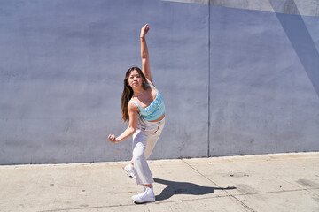 woman posing with arm extended in front of gray blue wall	