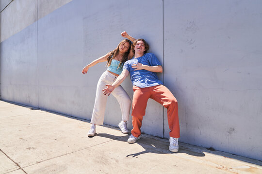 Woman and man posing close against gray blue wall	
