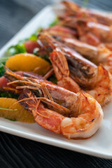 Grilled tiger prawns or shrimps with orange grapefruit and greens on a plate