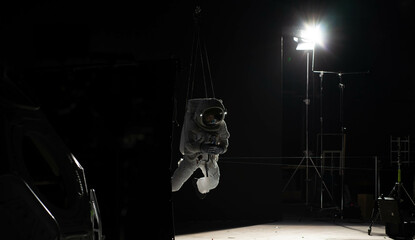 Behind the scenes of commercial shot - Caucasian female astronaut stuntwoman hanging on a wires,...