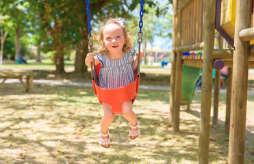 Child girl playing on outdoor playground. Kid play on school or kindergarten yard