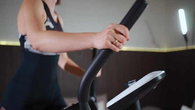 female running on elliptical orbitrek machine in fitness gym or apartment