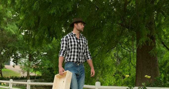 farmer working in a cornfield. Portrait of a handsome young farmer standing in a shirt and smiling. male farmer walks with a box through a farm in texas. a cowboy in a plaid shirt walks near the lake