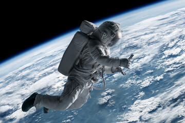 Caucasian female astronaut using her mobile phone during spacewalk near planet Earth, messaging, taking pictures - obrazy, fototapety, plakaty