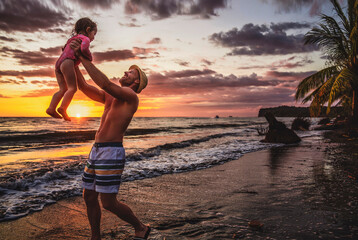 happy family at the beach a father and baby daughter having fun at sunset