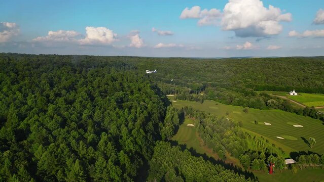 Drone beautiful view of summer nature, green forest mountains, blue sky and bright sunrise background. Helicopter biplane aircraft flying high above hills.
