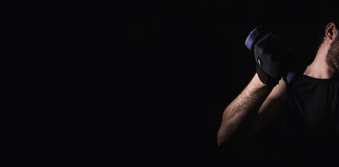 Young man practicing muscle and strength exercises with dumbbells. High intensity fitness. Copy space. Selective focus.