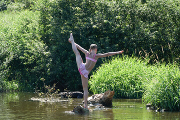 The girl does exercises on the river.