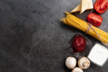 Background of cooking pasta and tagliatelle ingredients. Black background of Italian cuisine. View from above.