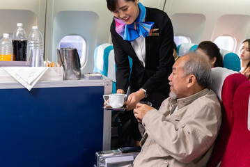 Young beautiful Asian flight attendant serving food and drink to passengers on airplane. Stewardess...