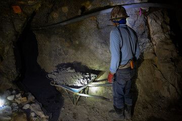A miner in a protective helmet with a flashlight and a dot in the Potosi mine. Bolivia