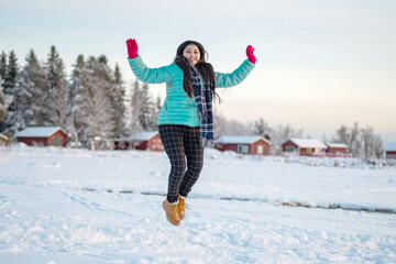  Portrait of a beautiful woman dressed with colourful jacket. A beautiful woman in coloured jacket walking through the Magical winter forest. Natural landscape with cloudy sky.