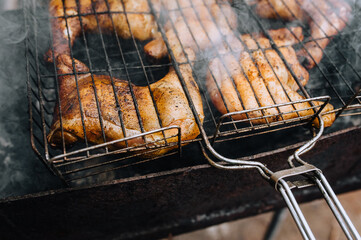 Chicken thighs are fried on the grill in a barbecue. Picnic in nature.