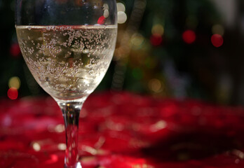 Glass of white wine with Christmas bokeh lights background 