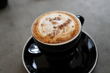 A close-up photo of a cup of cappuccino presented in a black cup.