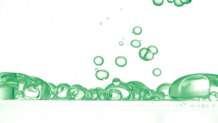Macro shot of green transparent different sized bubbles are falling down floating in transparent...