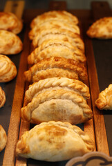 Empanadas tradicionales argentinas de hojaldre, rellenas  y recién horneadas en bandeja de madera © planeta11