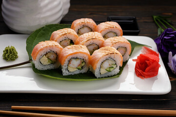 Maki sushi kimono with decor. on a plate, on a wooden background