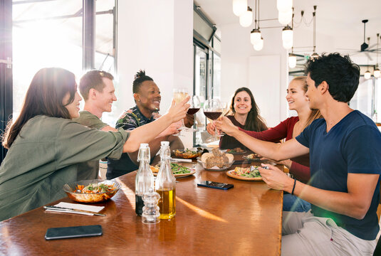 Smiling friends toasting with wine in restaurant