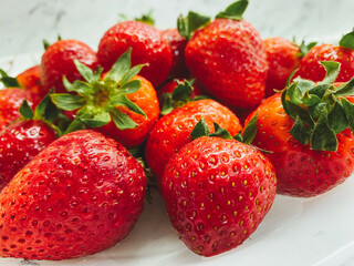 Red strawberries lie on a white table. Delicious, bright, sweet, healthy, vitamin strawberry. Dessert for a healthy diet.