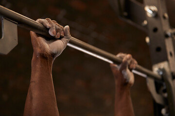 Close-up of mans hands with chalk lifting barbell in gym