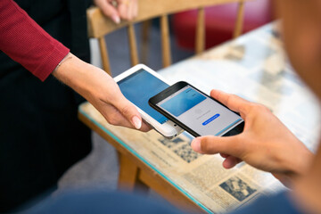 Close-up of man paying with smart phone in restaurant