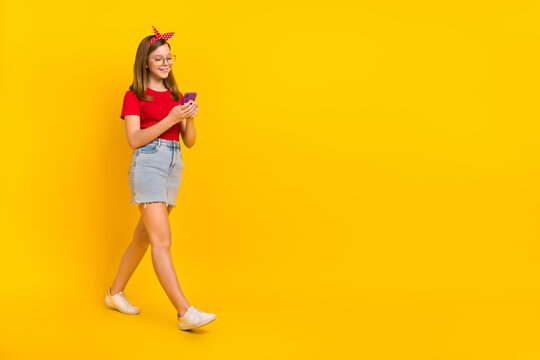 Full size photo of traveling little teen girl browsing fast speed in phone search information isolated on yellow color background