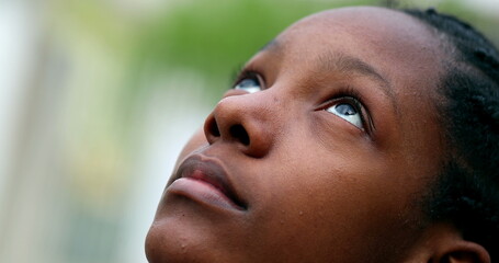 Black teen girl opening eyes to sky. African mix race adolescent woman smiling with HOPE and FAITH