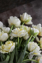 Bouquet of yellow tulips. Beautiful delicate flowers on a dark table. Buds with dew drops.