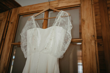 Fototapeta na wymiar Lace embroidery wedding dress hanging in the room.