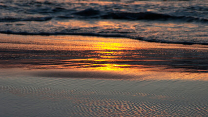 Sea waves and wet sand at sunset