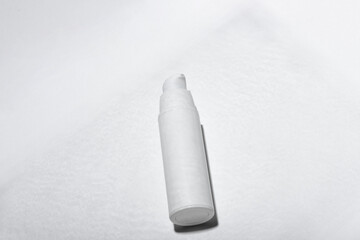 Cosmetic cream or mask in a white tube with hard shadows from the leaves on a white background. Natural organic care for face and body skin. View from above.