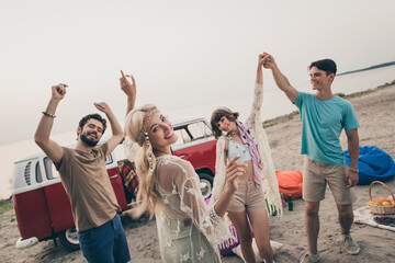 Photo of millennial chill friends dance celebrate holiday trip in minivan wear boho cloth outdoors