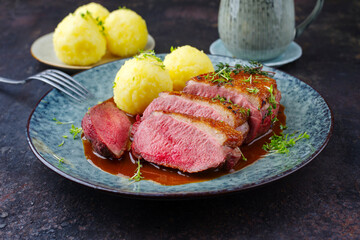 Traditionell gegrilltes Gourmet Entenbrust Filet mit Haut serviert mit Kartoffelknödeln in Dunkelbier Sauce als close-up auf einem Design Teller