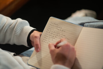 Close-up of young Caucasian man taking notes in notepad. Male student writing in notebook. Education concept - obrazy, fototapety, plakaty