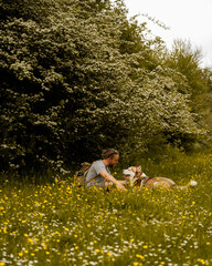 man and his dog sat in field of flowers
