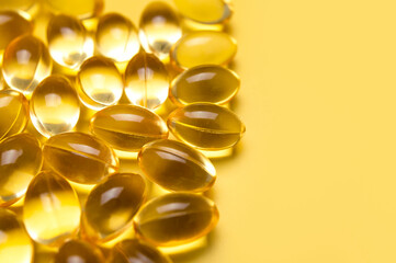 Capsules pill with vitamin D on yellow background close-up. Fish oil, Omega, Omega-3, dietary supplement, sunshine vitamin. Healthy lifestyle, medicine, cosmetology, diet. Pharmaceutical concept