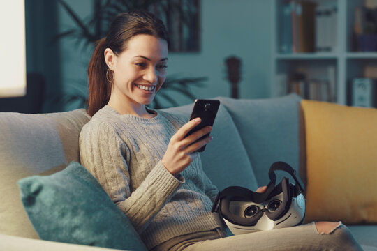 Smiling woman using her smartphone at home - Powered by Adobe