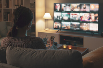 Woman watching TV at home and relaxing - obrazy, fototapety, plakaty