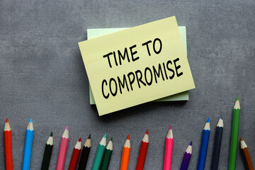 TIME TO COMPROMISE text on yellow sticker on gray background