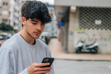 portrait of millennial teenager with mobile phone in the street