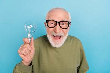 Portrait of attractive amazed cheery grey-haired man holding bulb new discovery explore isolated...