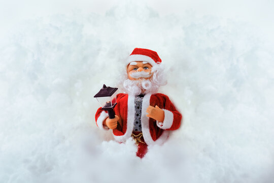 Toy doll Santa Claus on a white snowy background with space for text or image.