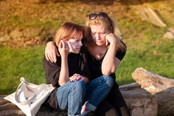 Teen girl in the park with mother relaxing, spending time together. The daughter tells  mother...