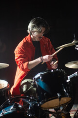 Enthusiastic young man playing drum set in studio. Portrait of male musician with moustache training on drum set or recording music. Drummer training concept