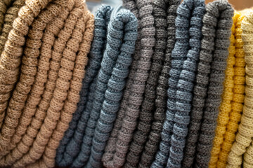 Stack of different colorful folded knitted scarfs texture. Stylish fall-winter season knitwear...
