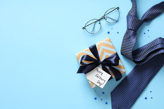 Happy Fathers Day concept. Flat lay composition with vintage gift box, eyeglasses, necktie on blue background.